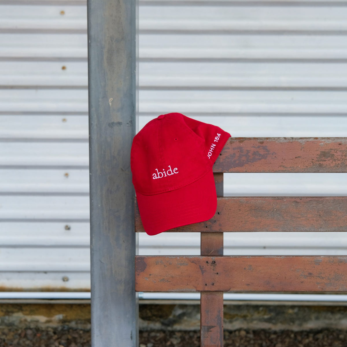 Abide Cap in red on a bench, John 15:4 on the side