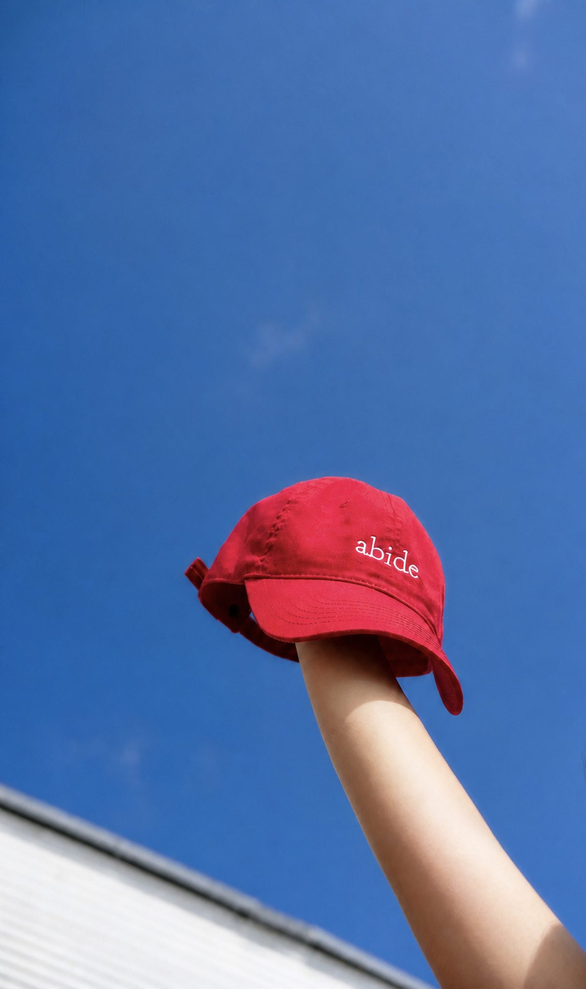 Abide Cap held up against a blue sky