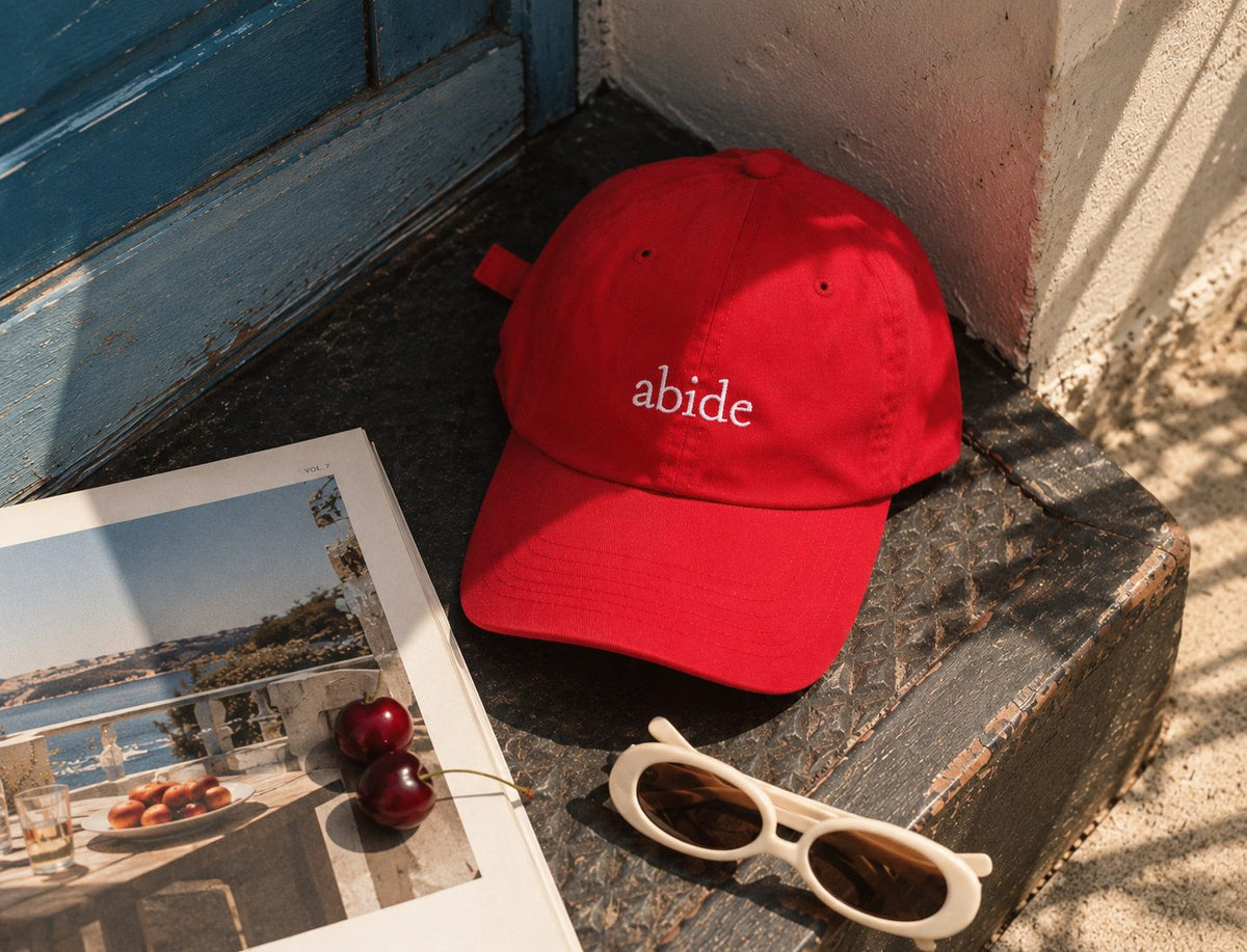 Abide Cap still life with a magazine and sunglasses